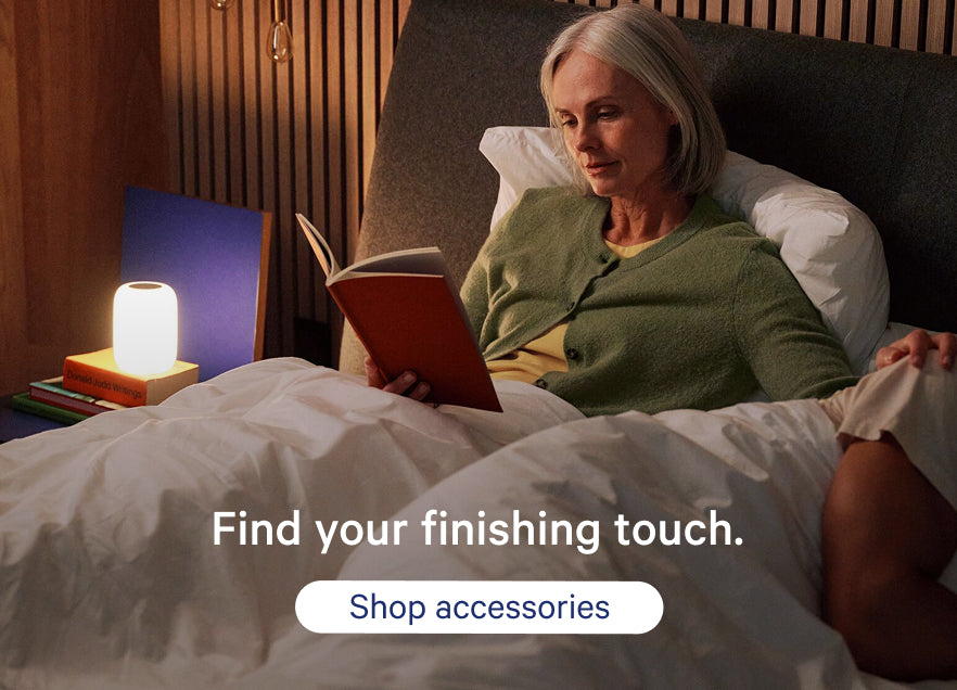 Woman reading a book in bed with a nightlight. Promotional text on the image says, "Find your finishing touch. Shop accessories."