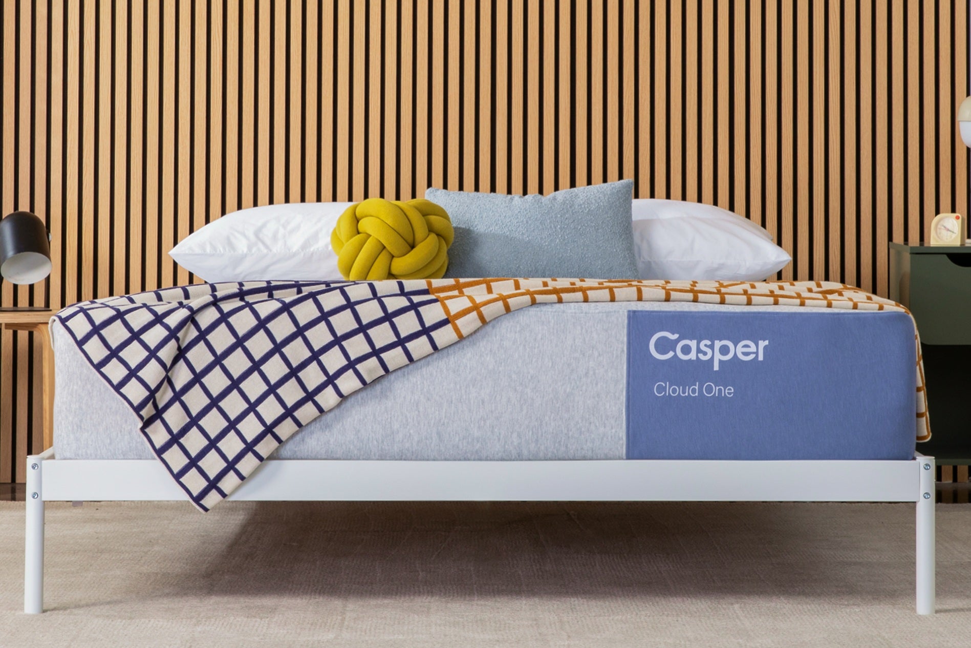 Casper's Cloud One mattress on a bed frame with pillows and a blanket folded on top