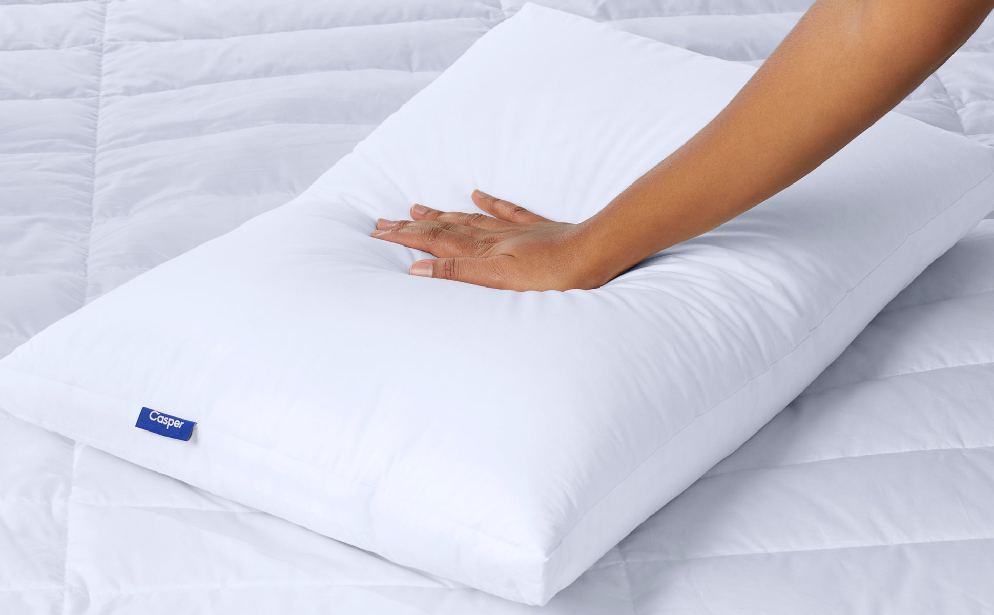 A hand feeling the Casper Down Pillow
