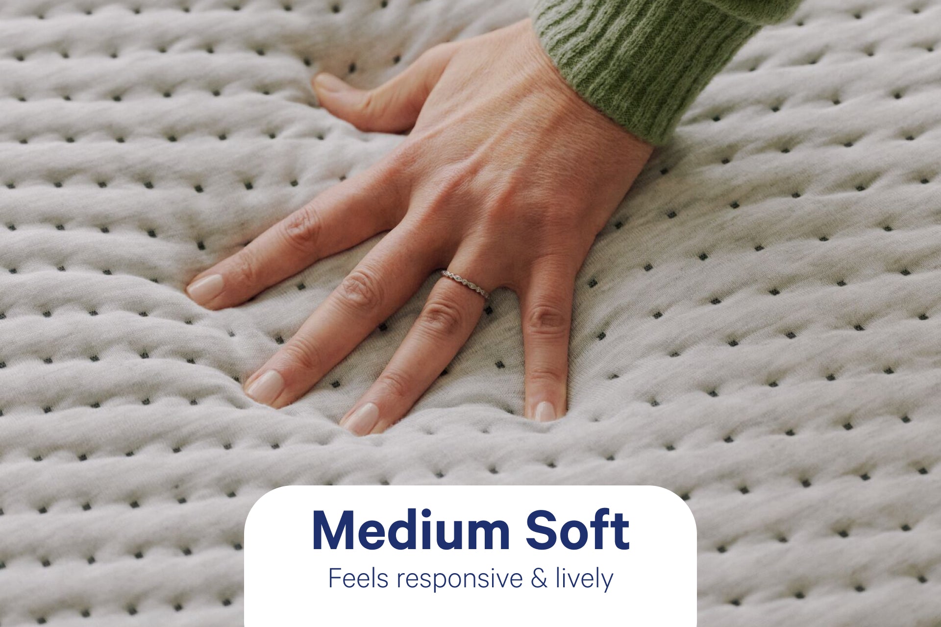 A person's hand pressing down to feel the Dream Max mattress. Text on the image indicates that its firmness level is Medium Soft and feels responsive & lively.