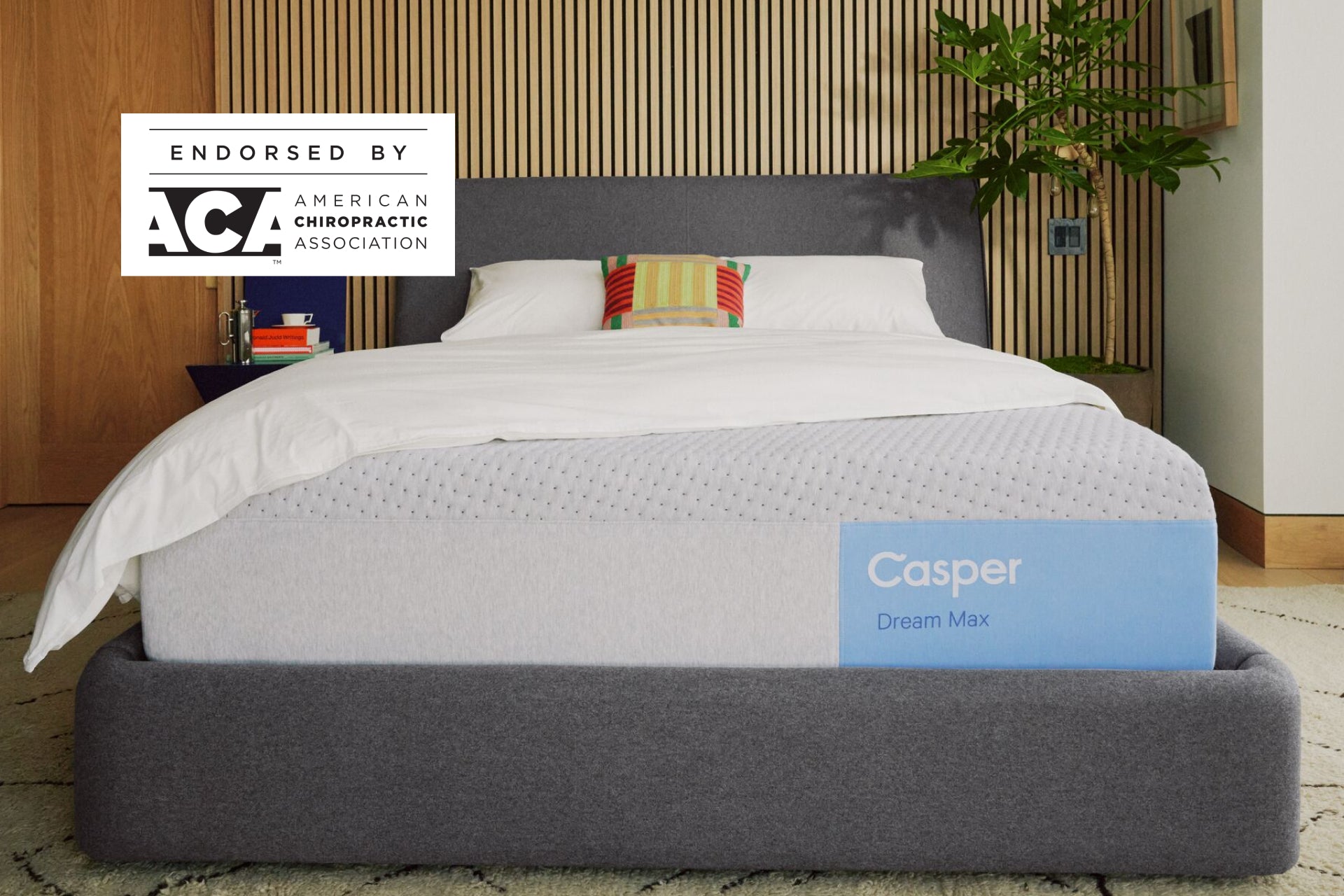 Casper's Dream Max mattress on a bed frame with pillows and a blanket folded on top. A badge on the image indicates that this mattress is endorsed by the American Chiropractic Association.