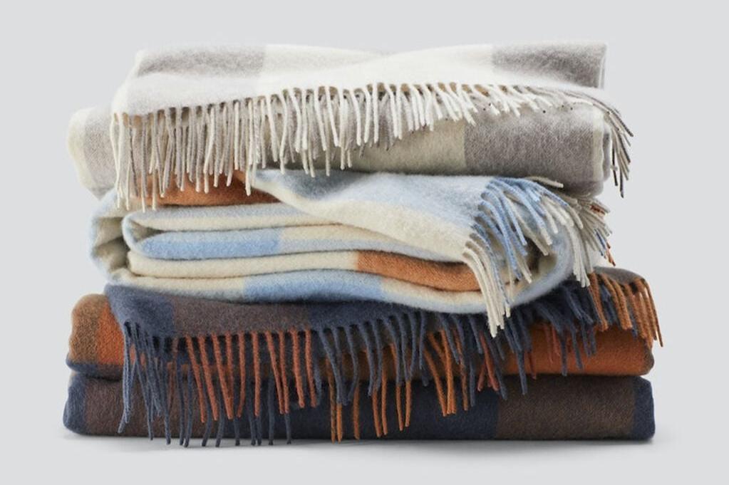 Various colored Bold Plaid Throw blankets, folded and stacked on top of each other