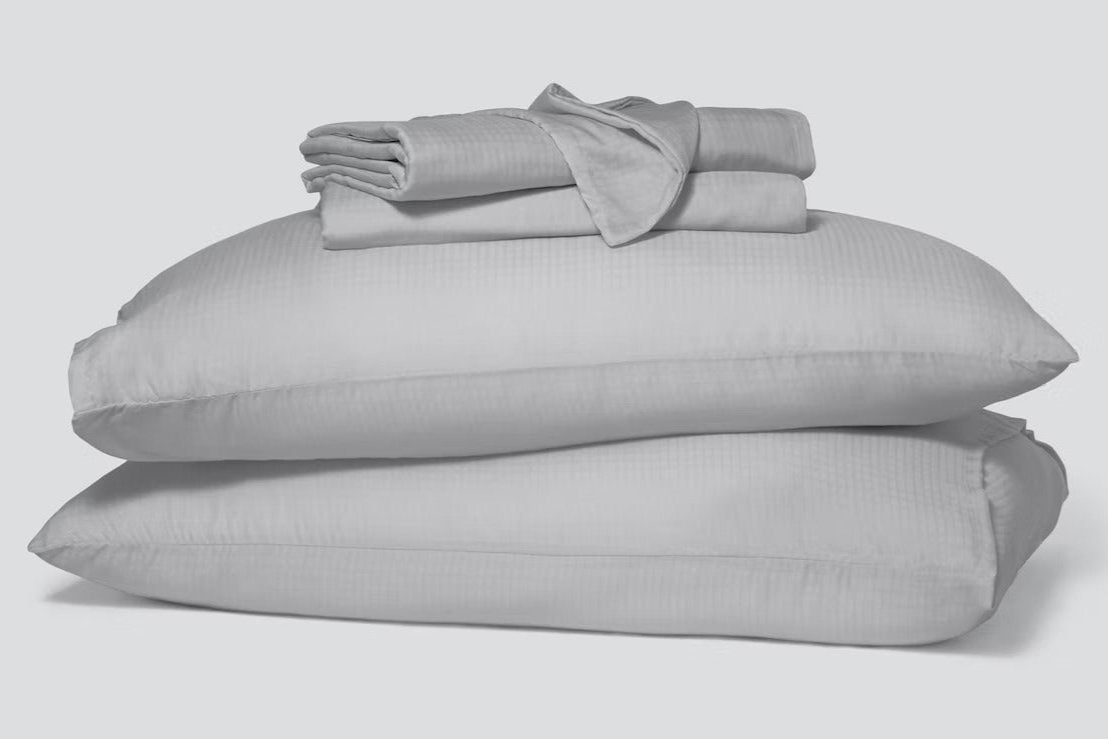 Folded pillowcases and a hyperlite sheet set, gray, sitting atop two pillows