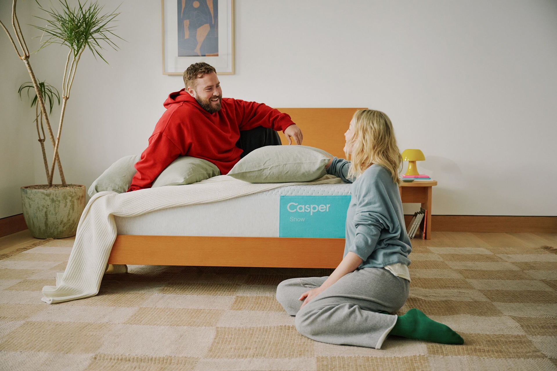 Lifestyle image of two people sitting and talking by their Casper Snow mattress.