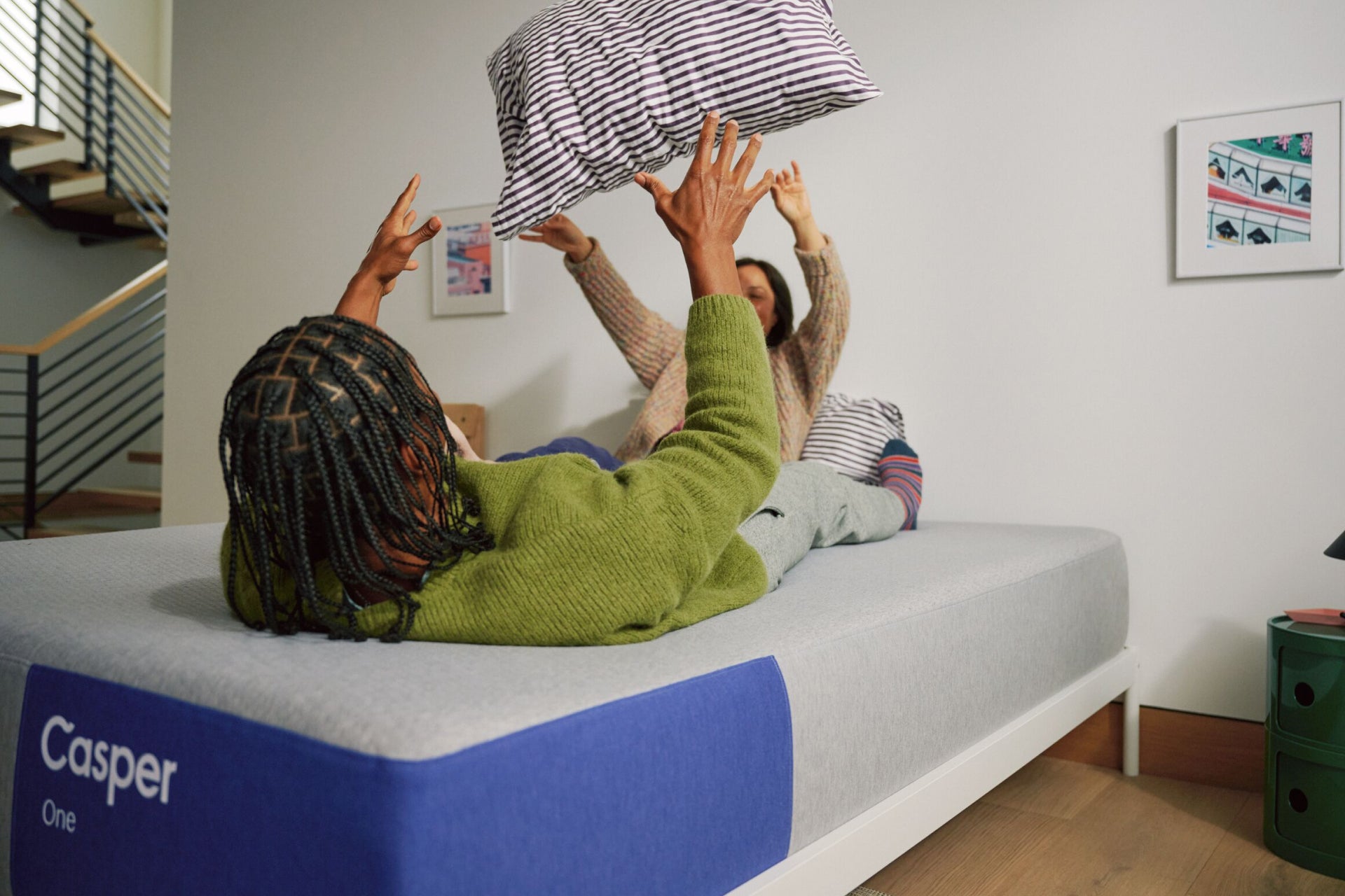 A couple lying on The One mattress tosses a pillow back and forth between themselves