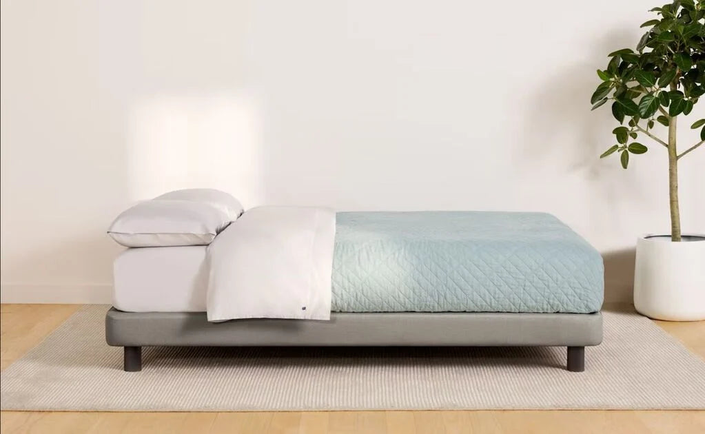 side view of a fully dressed bed on a gray upholstered bed frame