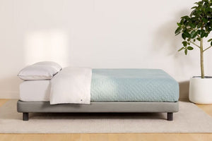 Side view of a fully made bed. The mattress sits atop Casper's Upholstered Bed Frame.