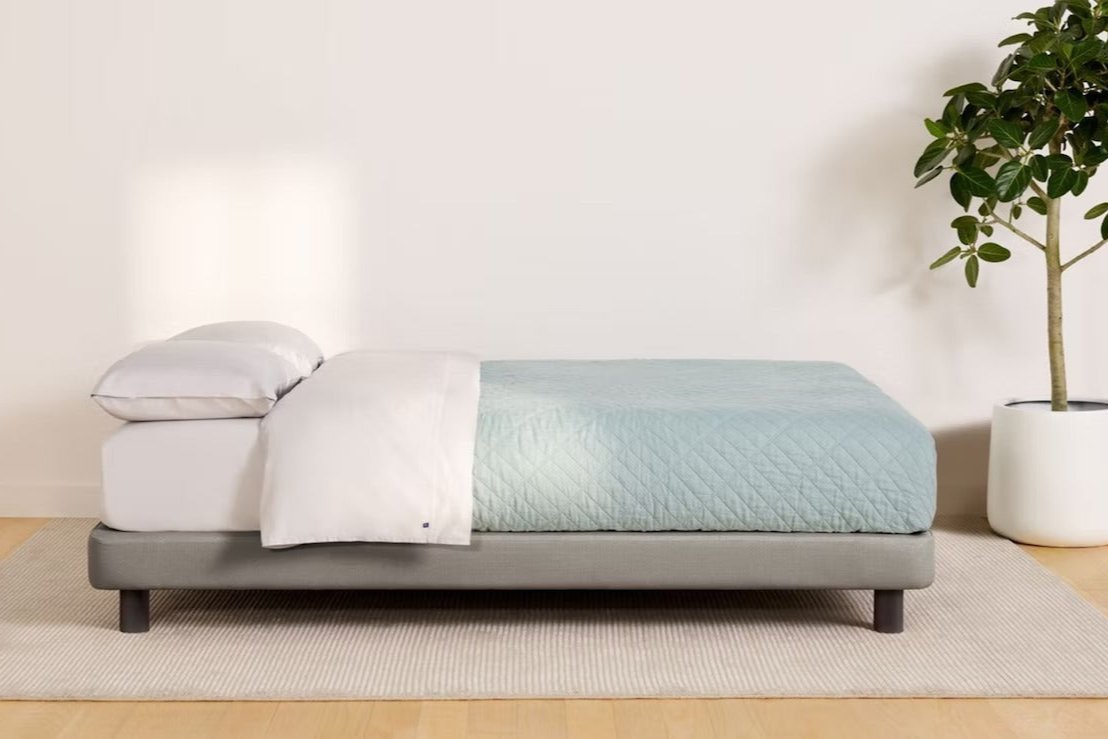 Side view of a fully made bed. The mattress sits atop Casper's Upholstered Bed Frame.