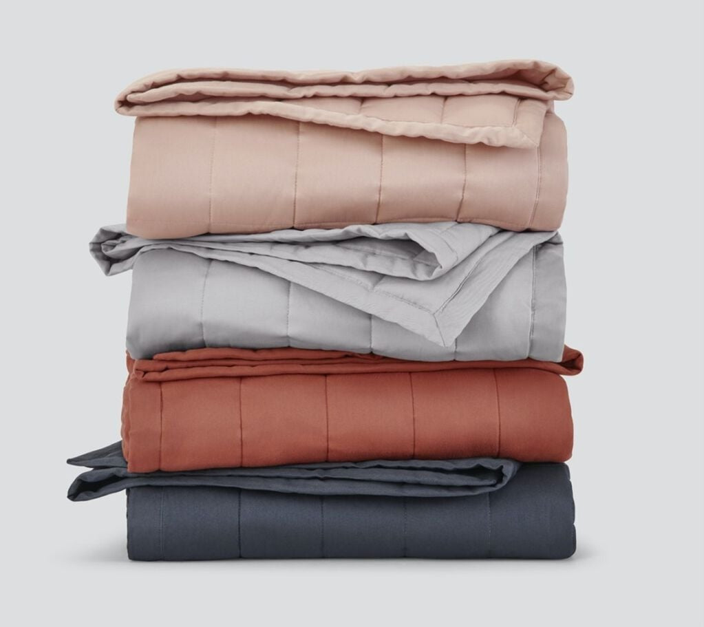 Multiple Weighted Blankets of assorted colors, folded and stacked on top of each other